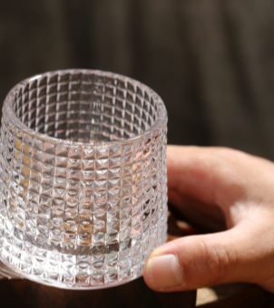 A top-down close-up shot of a clear barware whiskey tumbler, highlighting the smooth rounded rim, flawless waffle texture, and tapered lead-free glass body for hospitality sourcing.