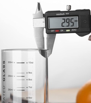 Quality control during the glassware production process The image shows the thickness of a glass being measured using vernier calipers. The glass has a capacity label, and the image illustrates the calibration of the accuracy of the glass measuring tool.