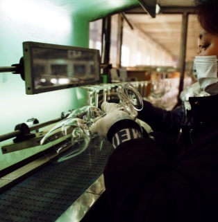Manual quality inspection and quality control of glass goblets Quality inspectors wear gloves and manually check the details and transparency of glass goblets under backlighting to ensure reliable product quality.