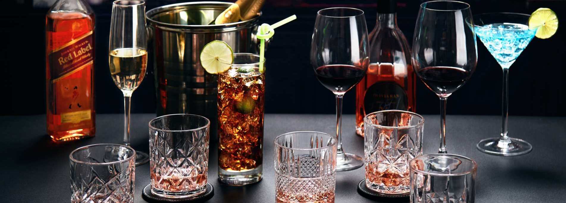 This is a product marketing poster, titled Xinghuo Glass Crystal Series Wine Glasses.jpg, taken in an elegant and sophisticated dimly lit bar or upscale banquet setting. The image showcases the exquisite engraving and multi-glass layout of Xinghuo Glass's